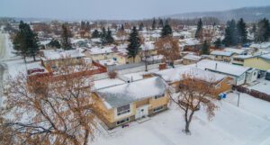 Aerial view of a snow-covered suburban neighborhood with houses and bare trees.